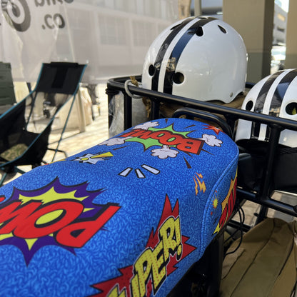 Comic Blast DiroDi Rover, Stator, Ampd Bros & Fatboy seat cover with vibrant comic-style graphics, soft neoprene, and bum protection for bold, comfy rides.