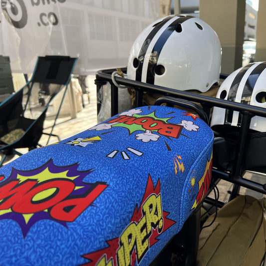 Comic Blast DiroDi Rover, Stator, Ampd Bros & Fatboy seat cover with vibrant comic-style graphics, soft neoprene, and bum protection for bold, comfy rides.